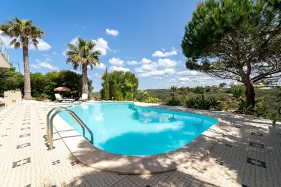 a swimming pool with a slide in a resort with palm trees at Duas Palmeiras in Aljezur