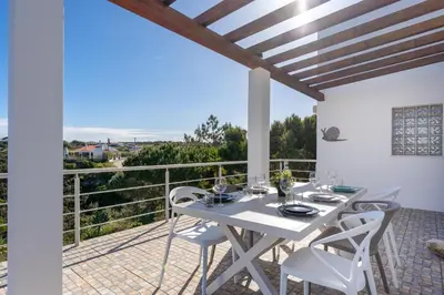 a white dining room with a table and chairs on a balcony at Duas Palmeiras in Aljezur