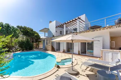 a villa with a swimming pool and an umbrella at Duas Palmeiras in Aljezur