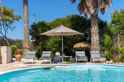 a swimming pool with chairs and an umbrella at Duas Palmeiras in Aljezur