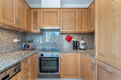 a kitchen with wooden cabinets and a stove top oven at Duas Palmeiras in Aljezur