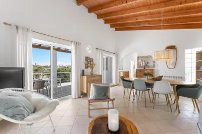 a dining room and living room with a table and chairs at Duas Palmeiras in Aljezur