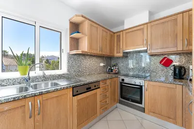 a kitchen with wooden cabinets and a sink and a window at Duas Palmeiras in Aljezur