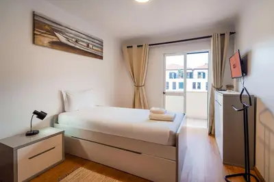 a white bedroom with a bed and a window at GuestReady - Machico Apartment with Balcony in Machico