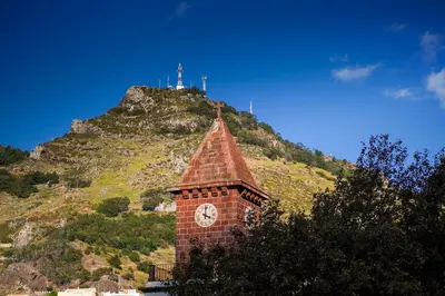 a clock tower with a mountain in the background at GuestReady - Machico Apartment with Balcony in Machico