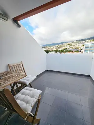 a balcony with chairs and a view of a city at Anadia Atrium in Funchal