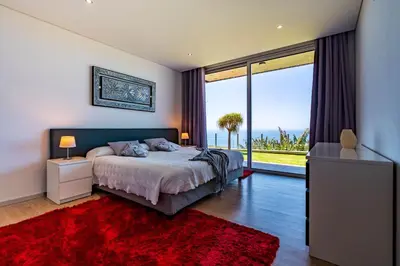 a bedroom with a bed and a large window at Villa Pinheira III heated pool in Calheta