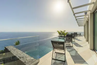 a balcony with a table and chairs and the ocean at Villa CLIFF HEAVEN HOUSE in Calheta