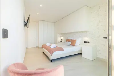 a bedroom with a large bed and a pink chair at Villa CLIFF HEAVEN HOUSE in Calheta