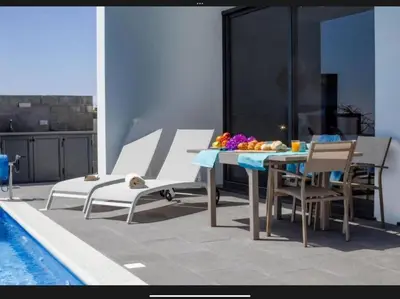 a patio with a table and chairs next to a pool at Villa Rubydom by Turin in Arco da Calheta