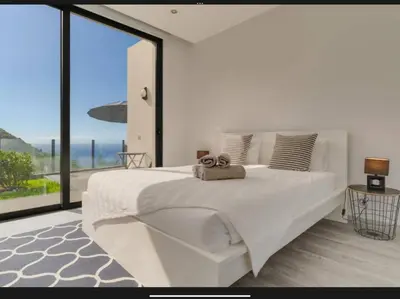 a white bedroom with a large bed and a large window at Villa Rubydom by Turin in Arco da Calheta