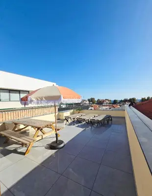 a patio with picnic tables and an umbrella on a roof at In City - Funchal Heart with Rooftop in Funchal