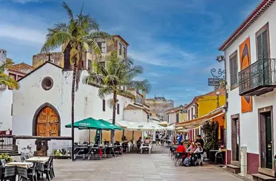 a city street with tables and chairs and palm trees at In City - Funchal Heart with Rooftop in Funchal