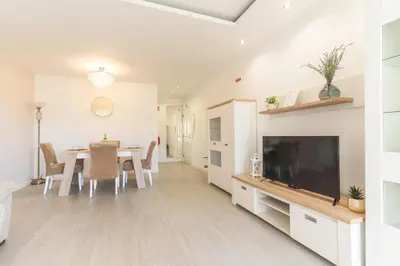 a living room with a dining room table and a television at Sol Garajau Apartment by Atlantic Holiday in Santa Cruz