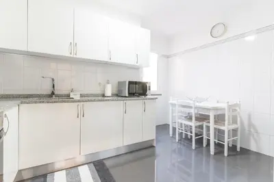 a white kitchen with a table and a microwave at Sol Garajau Apartment by Atlantic Holiday in Santa Cruz