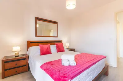 a bedroom with a large white bed with red pillows at Sol Garajau Apartment by Atlantic Holiday in Santa Cruz