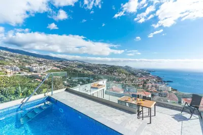 a villa with a swimming pool and a view of the ocean at Midnight House by Atlantic Holiday in Câmara de Lobos
