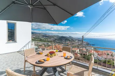 a wooden table with food on top of a balcony at Midnight House by Atlantic Holiday in Câmara de Lobos