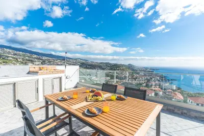 a wooden table on a balcony with a view of the ocean at Midnight House by Atlantic Holiday in Câmara de Lobos