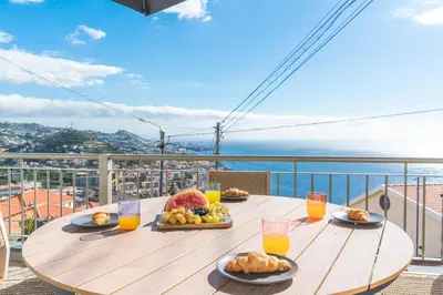 a wooden table with food on top of a balcony at Midnight House by Atlantic Holiday in Câmara de Lobos