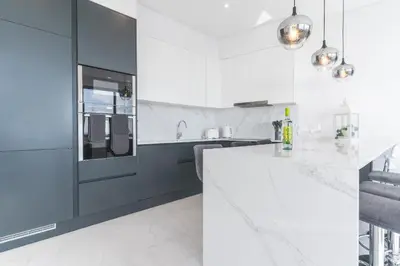 a white kitchen with black and white appliances at Midnight House by Atlantic Holiday in Câmara de Lobos