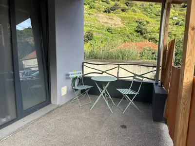 a balcony with a table and two chairs and a window at Cantinho S & F in Machico