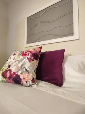 a bed with a pillow and a picture on the wall at Vitoria's Vale in Funchal