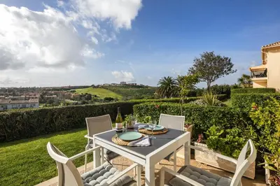 a table and chairs on a patio with a view at Fairview Golfside Apartment at Boavista in Atalaia