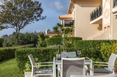 a table with two chairs and a bottle of wine at Fairview Golfside Apartment at Boavista in Atalaia