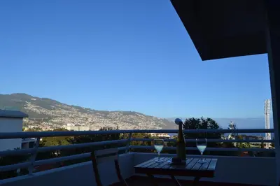 a balcony with a table with wine glasses on it at Ocean View II in Funchal