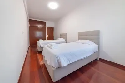 a bedroom with two beds with white sheets and wood floors at Esmael Apartment By Mth in Funchal