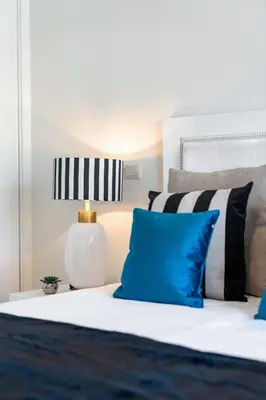a bed with blue and white pillows and a lamp at Casa Branca Penthouse by An Island Apart in Funchal