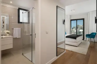 a bathroom with a glass shower and a bedroom at Casa Branca Penthouse by An Island Apart in Funchal