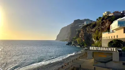 a sign for a restaurant next to the ocean at Sea Front in Câmara de Lobos