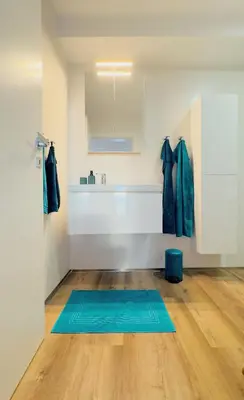 a bathroom with a blue rug on a wooden floor at Sea Front in Câmara de Lobos