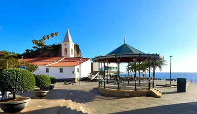 a building with a gazebo next to the ocean at Sea Front in Câmara de Lobos