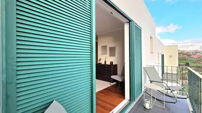 a room with a balcony with two chairs and a window at Atlantic Breeze in Câmara de Lobos