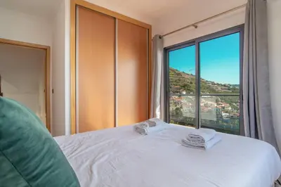 a bedroom with a white bed with a large window at Camara De Lobos Lux Villa in Câmara de Lobos