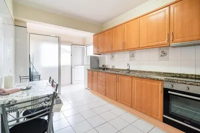 a kitchen with wooden cabinets and a table in it at GuestReady - Machico Apartment with Balcony in Machico