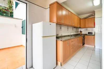 a kitchen with wooden cabinets and a white refrigerator at GuestReady - Machico Apartment with Balcony in Machico