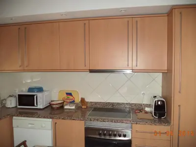 a kitchen with wooden cabinets and a stove and a microwave at St James Apartment in Luz