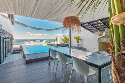 a dining room with a table and a swimming pool at Villa Lázaro By Holiday Rental Madeira in Funchal