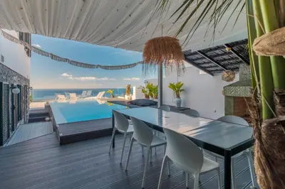 a dining room with a table and a swimming pool at Villa Lázaro By Holiday Rental Madeira in Funchal