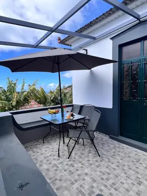 a table and chairs with an umbrella on a patio at Bravas House 1 in Tábua
