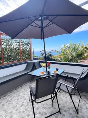 a table and chairs with an umbrella on a balcony at Bravas House 1 in Tábua