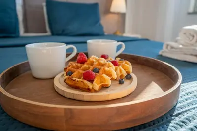 a plate of waffles and berries on a table with two cups at Beachfront Flat & Panoramic Sea View by HostWise in Luz