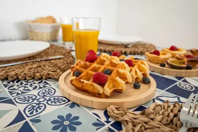 a table topped with waffles with berries and oranges at Beachfront Flat & Panoramic Sea View by HostWise in Luz