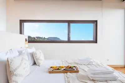a white bedroom with a bed with a tray of fruit on it at Casa Vista Azul by Atlantic Holiday in Santo da Serra
