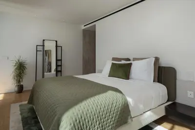 a bedroom with a large bed with white sheets and green pillows at Savoy Monumentalis X by An Island Apart in Funchal