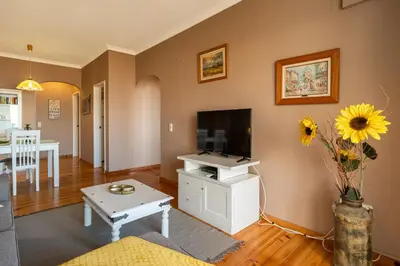 a living room with a tv and a vase with a sunflower at Atlantic Ocean by Holiday Rental Madeira in Funchal